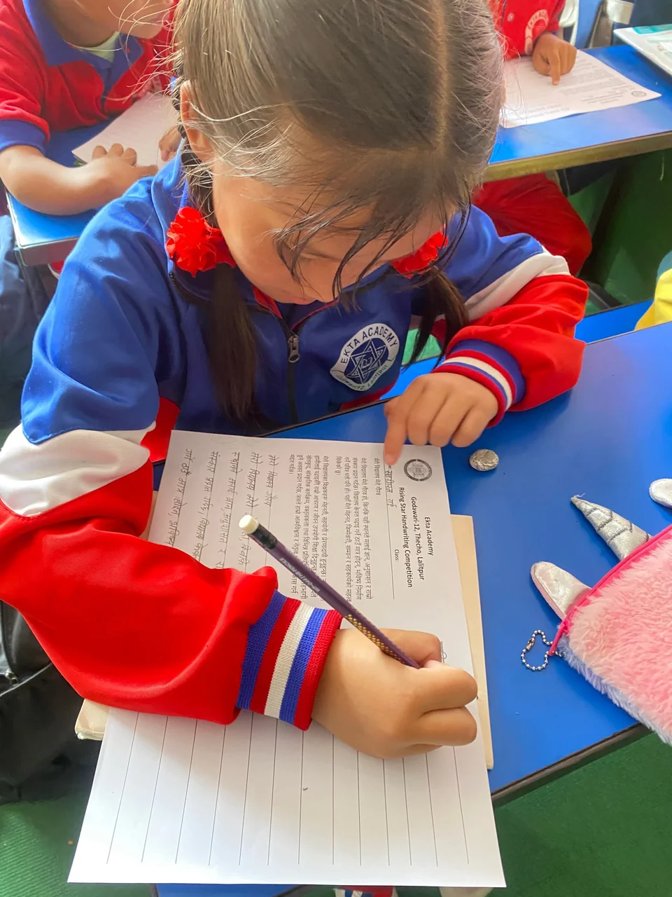 Anak fokus menulis di meja kelas
