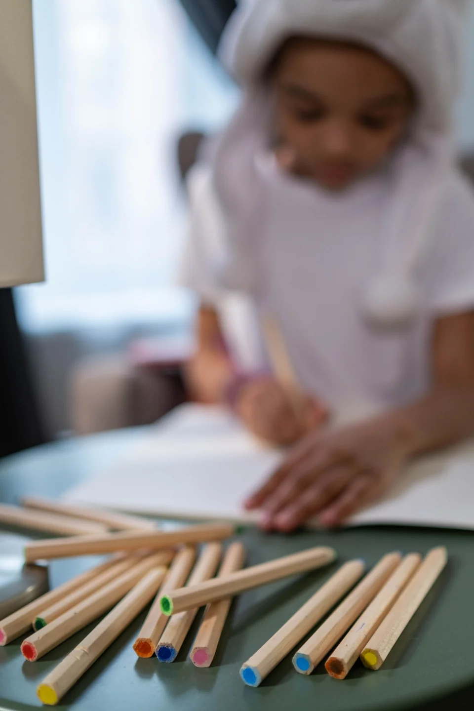 Anak fokus menggambar dengan pensil warna di meja